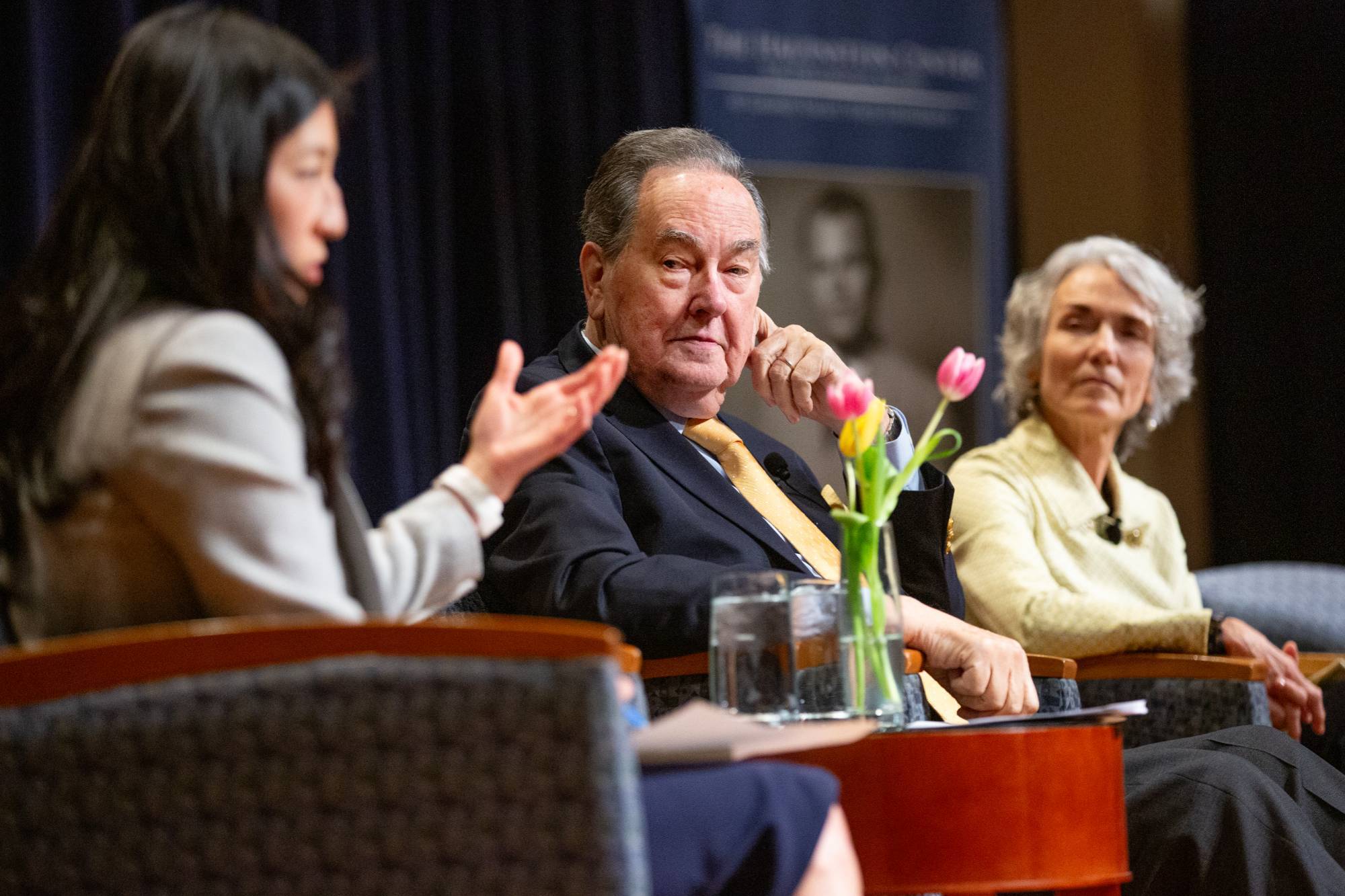 Hauenstein Center DIrector Megan Rydecki speaks from the stage as guest panelists Cal Thomas and Elizabeth Cobbs look on.